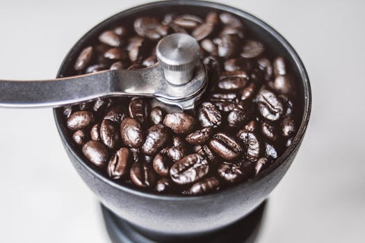 Close-up of roasted coffee beans in a manual grinder, capturing rich textures and aroma.