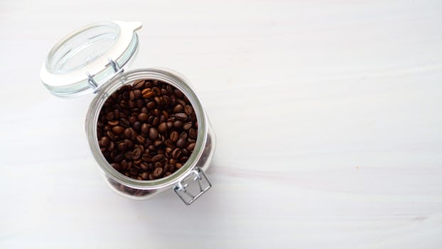 Top view of a glass jar filled with aromatic roasted coffee beans.